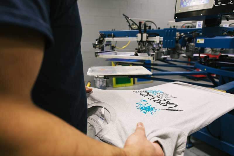 A staff member inspecting high-quality printed t-shirts